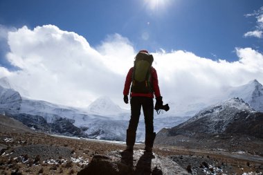 Yüksek irtifa dağlarında kameralı bir kadın yürüyüşçü.