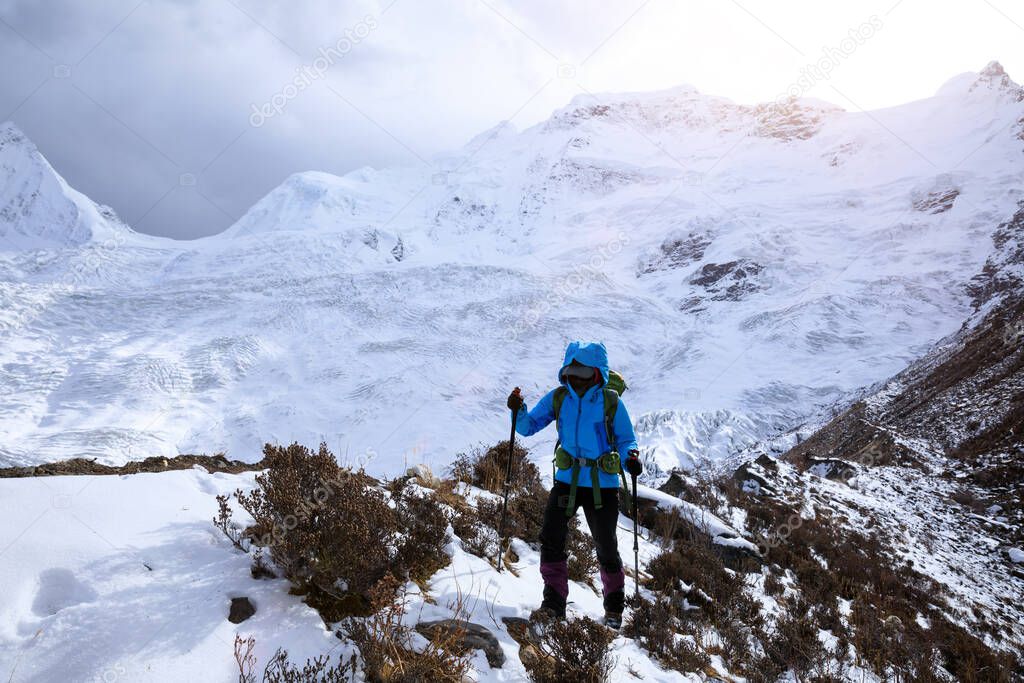 Successful woman backpacker hiking in winter mountains