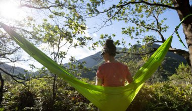 Tropikal ormanda akıllı telefon kullanarak hamakta dinleniyor.