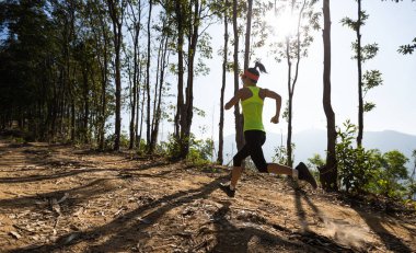 Gündoğumunda tropik orman zirvesinde koşan fitness kadın patika koşucusu
