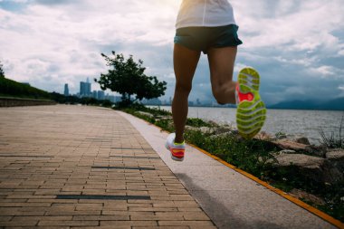 Spor salonundaki kadın güneşli sahil yolunda maratona hazırlanıyor.