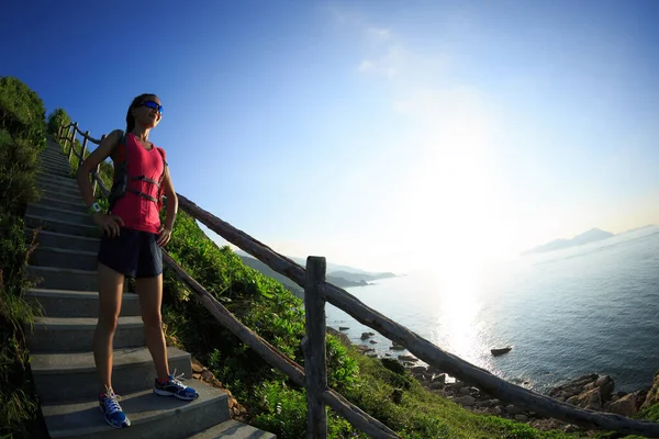 成功的健美女子赛跑选手在海滨山区的楼梯上欣赏风景 — 图库照片