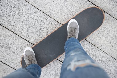 Kaykaycı bacakları açık havada kaykay yapıyor.