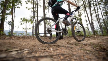 Dağın tepesinde bisiklet süren bir kadın.