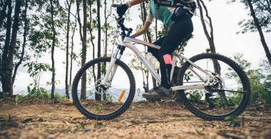 Dağın tepesinde bisiklet süren bir kadın.