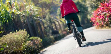 Bahar tropik parkında bisiklet süren bir kadın