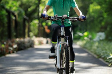 Güneşli bir günde parkta bisiklet süren bir kadın.