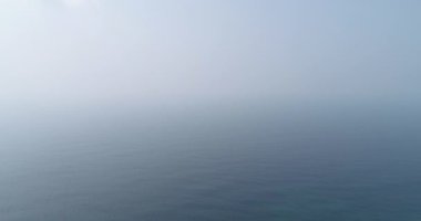 Denizin sisli manzarası, dalgalar hareket ediyor.