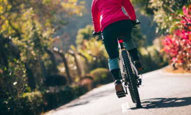 Bahar parkında tropik bisiklet süren bir kadın. 