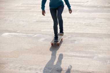 Kaykaycı bacakları açık havada kaykay yapıyor.