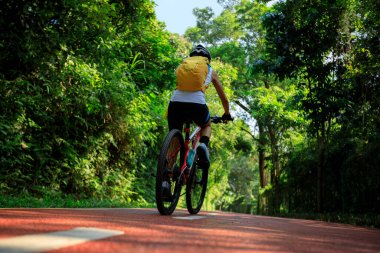 Gündoğumu parkında bisiklet yolunda bisiklet süren bir kadın