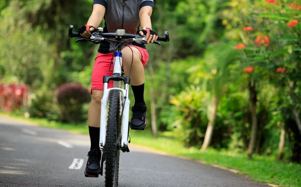 Woman cycling on tropical park trail in summer