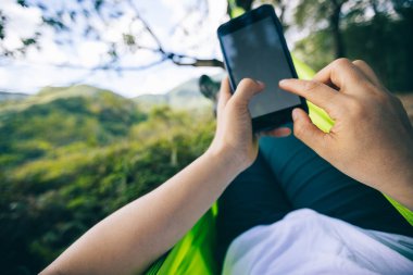 Tropikal yağmur ormanlarında akıllı telefon kullanarak hamakta dinlenmek