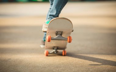 Kaykaycı bacakları açık havada kaykay yapıyor.