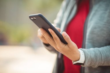 Şehirde akıllı telefon kullanan Asyalı bir kadın.