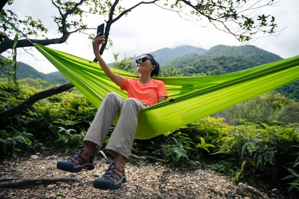 热带森林中使用智能手机在吊床上放松 — 图库照片