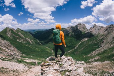 Başarılı bir kadın sırt çantalı dağ zirvesinde yürüyüş yapıyor.