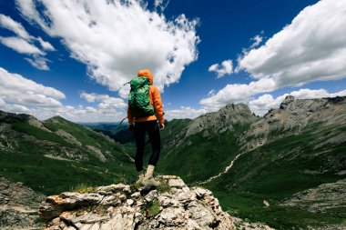 Başarılı bir kadın sırt çantalı dağ zirvesinde yürüyüş yapıyor.