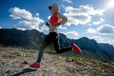 Genç kadın ultra-maraton koşucusu dağın tepesinde koşuyor.