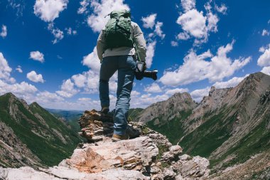 Yükseklerdeki dağın tepesinde kameralı başarılı bir kadın yürüyüşçü.