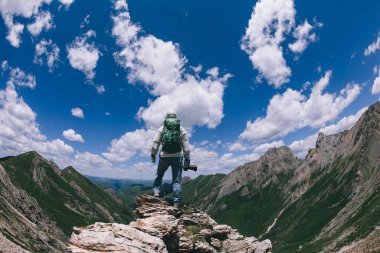 Yükseklerdeki dağın tepesinde kameralı başarılı bir kadın yürüyüşçü.
