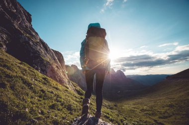 Başarılı bir kadın sırt çantalı. Gün batımı dağlarının tepesinde yürüyüş yapıyor.