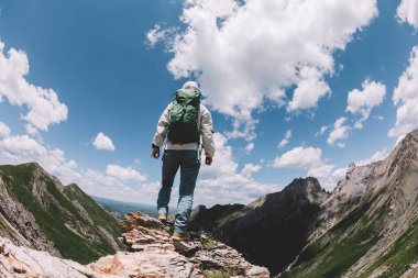 Başarılı bir kadın sırt çantalı dağ zirvesinde yürüyüş yapıyor.