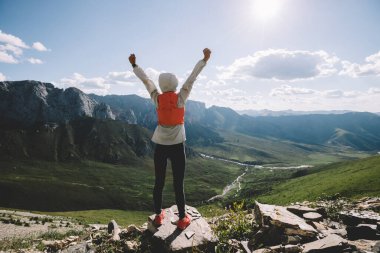 Başarılı bir kadın sırt çantalı. Gün batımı dağlarının zirvesinde yürüyüş yapıyor.