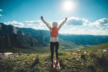 Başarılı bir kadın sırt çantalı. Gün batımı dağlarının zirvesinde yürüyüş yapıyor.