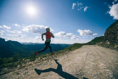 Genç kadın ultra-maraton koşucusu dağın tepesinde koşuyor.