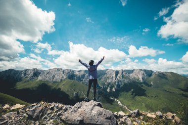 Günbatımı dağlarının zirvesinde başarılı bir kadın yürüyüş yapıyor.