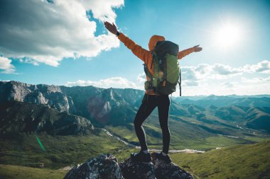 Başarılı bir kadın sırt çantalı dağ zirvesinde yürüyüş yapıyor.