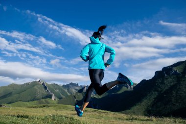 Dağın tepesinde koşan genç bir kadın koşucu.