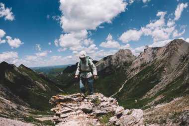 Yüksek rakımlı dağın tepesinde kameralı bir kadın yürüyüşçü.