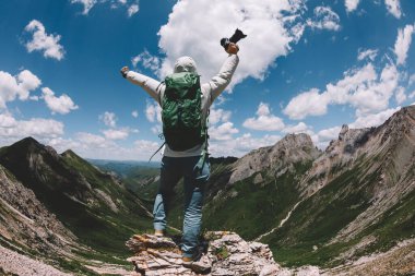 Yükseklerdeki dağın tepesinde kameralı tezahürat yapan kadın fotoğrafçı.