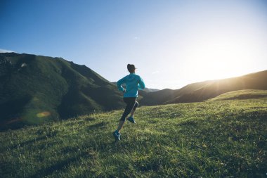 Genç bayan koşucu dağın tepesinde koşuyor.