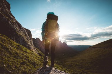 Başarılı bir kadın sırt çantalı. Gün batımı dağlarının tepesinde yürüyüş yapıyor.