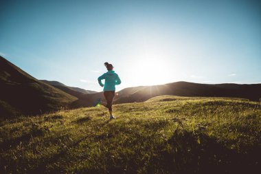 Genç bayan koşucu dağın tepesinde koşuyor.