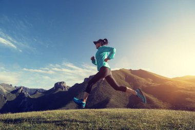 Genç bayan koşucu dağın tepesinde koşuyor.