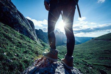 Başarılı bir kadın sırt çantalı. Gün batımı dağlarının zirvesinde yürüyüş yapıyor.