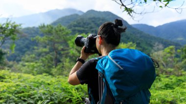 Kadın fotoğrafçı yaz dağlarında fotoğraf çekiyor.
