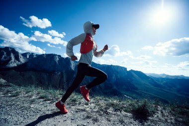Genç kadın ultra-maraton koşucusu dağın tepesinde koşuyor.