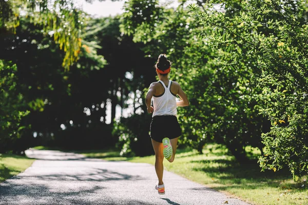 健康的女人在阳光灿烂的热带公园小径上奔跑 — 图库照片