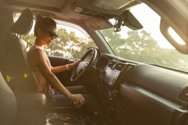 Güneş doğarken dağ yolunda araba süren kadın.