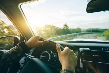 İnsanlar gün doğumunda dağ yolunda araba kullanıyorlar.