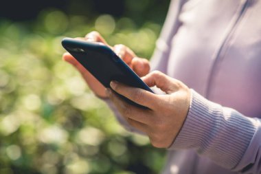 Açık havada akıllı telefon kullanan Asyalı kadın.