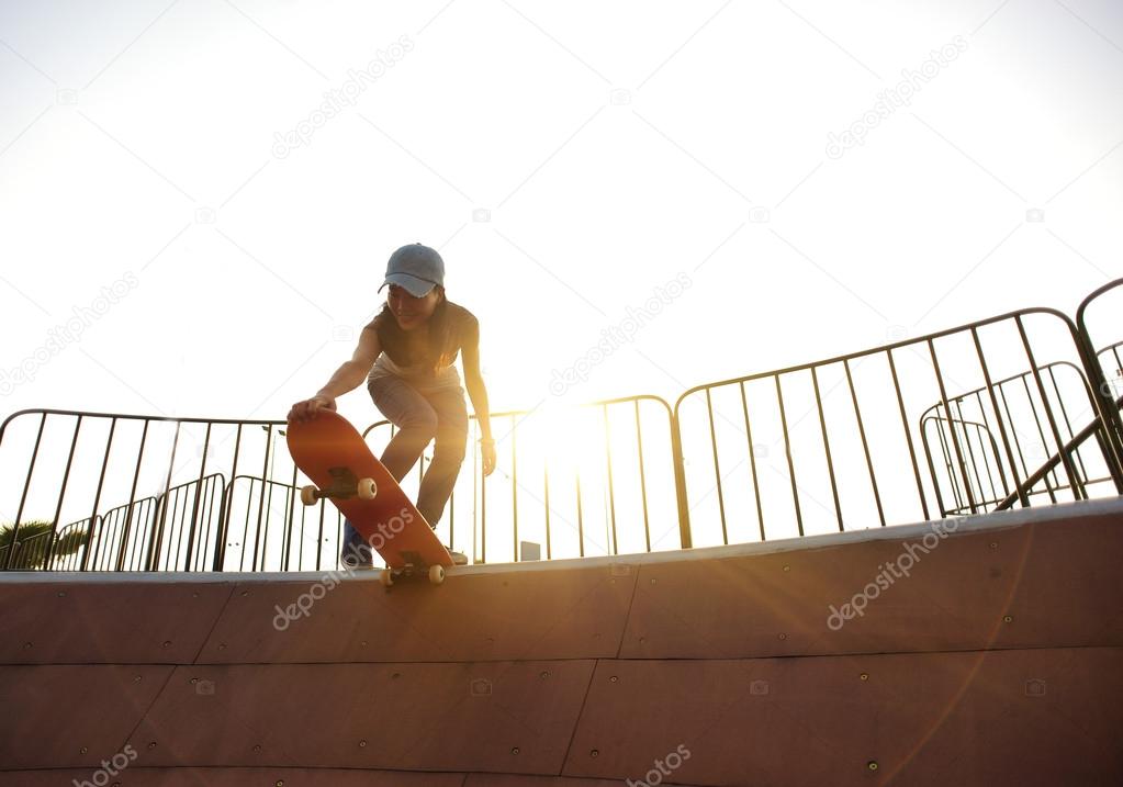 Young woman skateboarding at sunrise