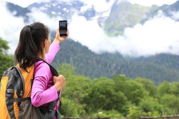 Mujer excursionista tomando fotos con teléfono celular en el pico de la montaña en el Tíbet, China —  Fotos de Stock