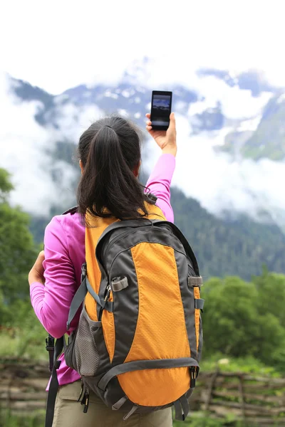 Mujer excursionista tomando fotos con teléfono celular en el pico de la montaña en el Tíbet, China —  Fotos de Stock