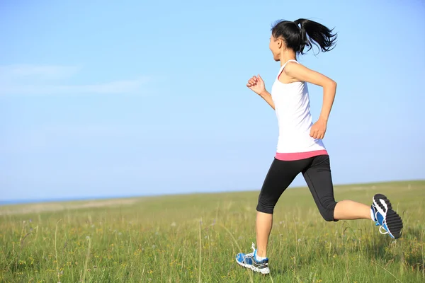 Sportovec běžec běží na trávě přímořské. — Stock fotografie